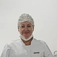 Roberta Teodoro, podóloga, sorrindo, de jaleco branco, no consultório